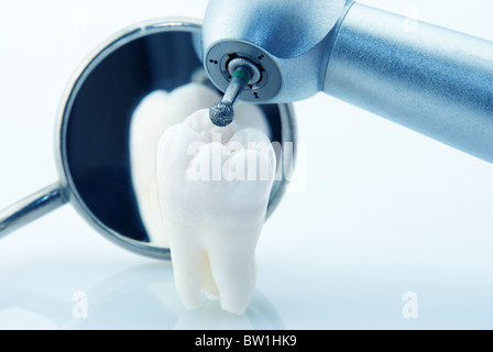 Gesunde Zähne-Konzept. Echte menschliche Weisheitszahn Mundspiegel und Maschine mit Bohrer. Blau getönte Bild Stockfoto