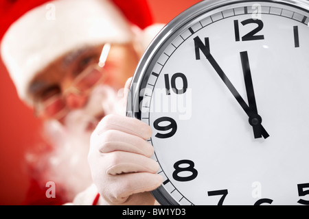 Foto der Uhr zeigt fünf Minuten bis Mitternacht mit dem Weihnachtsmann auf Hintergrund Stockfoto