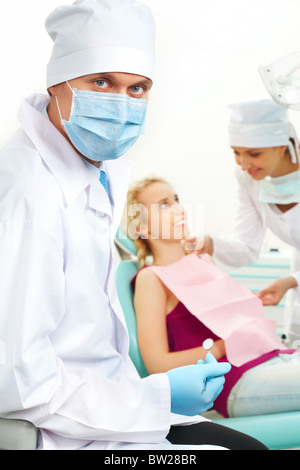 Porträt von zuversichtlich Arzt in sterilen Maske auf Grund seines Assistenten helfen Patienten Stockfoto