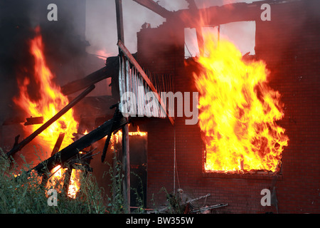 Haus in Brand und zerstörten. Mauer und Terrasse in vollen Flammen und Rauch. Totalen Verlust und Zerstörung. Nachtzeit. Stockfoto