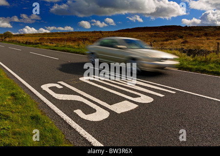Schnell bewegenden Auto neben langsamen Schild gemalt auf Landstraße in Großbritannien warnen Autofahrer zu verlangsamen Stockfoto