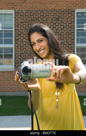 Junge Frau mit Video-Kamera, Camcorder, außerhalb der Schule in Winnipeg, Manitoba, Kanada. Stockfoto