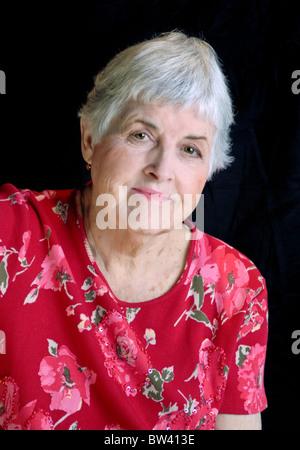 Ein lebendige Senioren Frau mit weißem Haar, trägt ein rotes geblümtes Hemd und lächelnd. Stockfoto