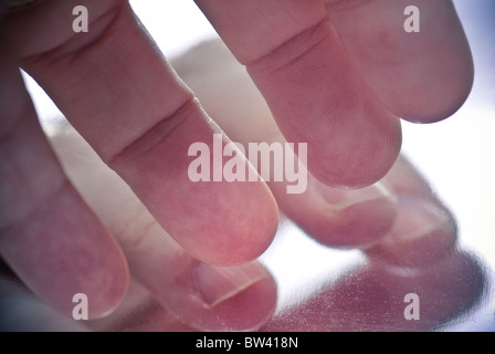 Eine abstrakte Makro der Finger, auf eine glänzende, reflektierende Oberfläche gespiegelt. Stockfoto