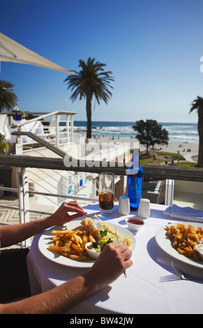 Frau Essen Fish &amp; Chips in Restaurant, Camps Bay, Cape Town, Western Cape, Südafrika Stockfoto