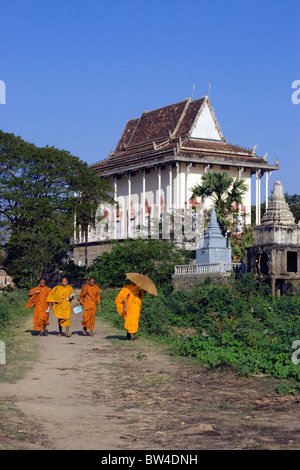 Schulklassen in Kampong Cham, Kambodscha gehen vier buddhistische Mönche, die in Bangkok Tempel Wat (Hintergrund) Leben. Stockfoto