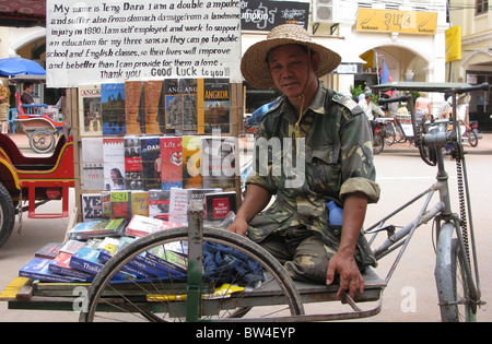 Ein doppelt amputierten Landminen-Opfer und seine mobile Buch stall in Siem Reap. Stockfoto