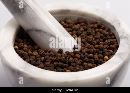 Grauen und weißen Mörser gefüllt mit schwarzen heiße würzige Pfefferkörner Stockfoto