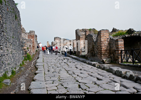 Touristen Fuß entlang einer geraden römische Straße grenzt an jeder Seite von Ruinen der Häuser und Geschäfte, Pompeji, Italien Stockfoto