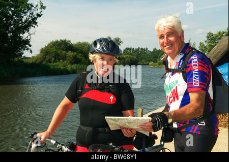 zwei Reife Radfahrer Karte lesen und in die Kamera schaut, während am Rand der Norfolk Broads Stockfoto