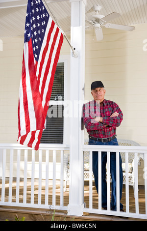 Senior Mann, die amerikanische Flagge auf Veranda Stockfoto