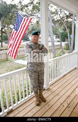 Senior Woman im militärischen uniform stehen durch die amerikanische Flagge auf Veranda Stockfoto