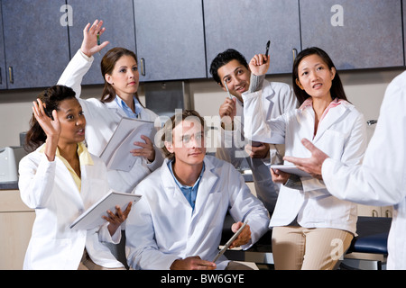Medizinstudenten in der Klasse Hände erhebend Stockfoto
