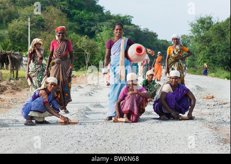 Bande der indischen Frauen Straßenarbeiter fegen und sammeln sie Steine auf eine neu angelegte Straße vor der Oberfläche angewendet wird. Andhra Pradesh, Indien Stockfoto