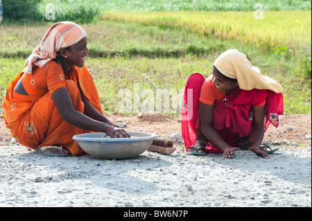 Indische Frauen Straßenarbeiter fegen und Kommissionierung bis Steine mit der Hand eine neu angelegte Straße vor der Oberfläche angewendet wird. Andhra Pradesh, Indien Stockfoto