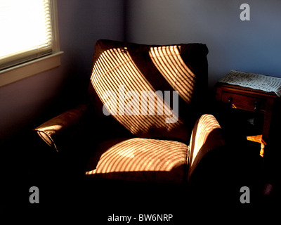 Sofa weichen Sessel Stoff mit Sonne Muster aus nahe gelegenen Fenster mit Streifen plus Holz Beistelltisch Stockfoto