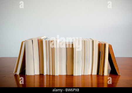 Eine Reihe von Büchern sitzt auf einem Holz-Tisch mit Leerzeichen hinter Stockfoto