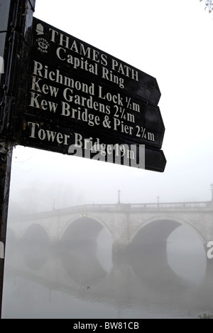 an einem nebligen Tag, ein Wegweiser und Wegbeschreibungen von Richmond nach Themse, Surrey, England, mit Richmond Bridge im Hintergrund zu sehen Stockfoto