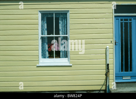 Schiebefenster in gelb lackierten Schindeln Haus mit blauen Tür Stockfoto