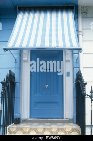 Blau + weiß gestreifte Markise über blaue Haustür in blassen blauen Traditionshaus in Nahaufnahme Stockfoto