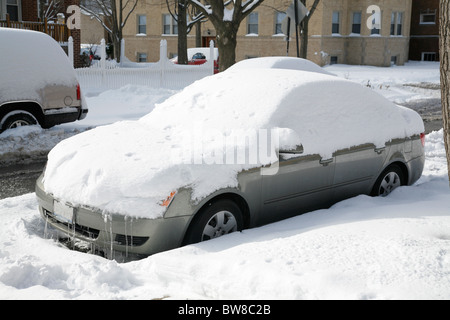 Schnee bedeckt und umgibt ein Auto auf einer Stadtstraße im winter Stockfoto