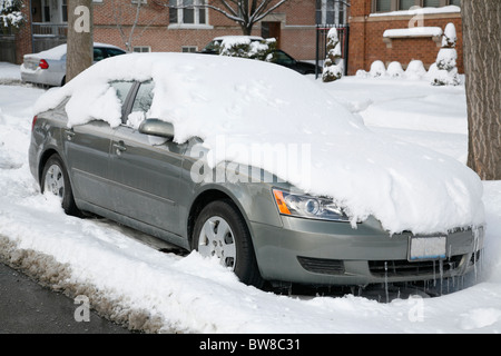 Schnee bedeckt und umgibt ein Auto in einer Seitenstraße Stadt im winter Stockfoto