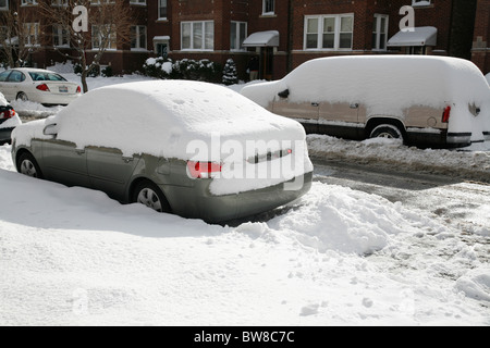 Schnee bedeckt und umgibt ein Auto und LKW geparkt auf einer Straße im winter Stockfoto