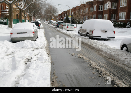 Schnee bedeckt und umgibt Autos parkten auf einem gepflügten Stadtstraße im winter Stockfoto
