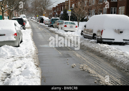 Schnee bedeckt und umgibt Autos parkten auf einem gepflügten Stadtstraße im winter Stockfoto