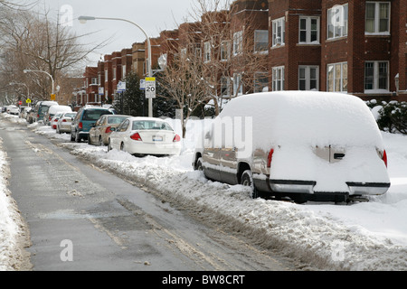 Schnee bedeckt und umgibt Autos parkten auf einem gepflügten Stadtstraße im winter Stockfoto