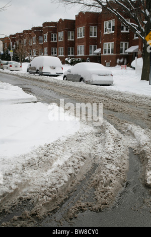 schmutzigen Schnee umgibt Autos parkten in einer Seitenstraße Gepflügtes Stadt mit Reifenspuren im winter Stockfoto