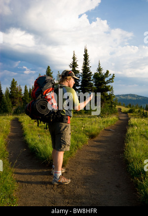 Ein Wanderer prüft seine GPS-Gerät an einer Weggabelung Stockfoto