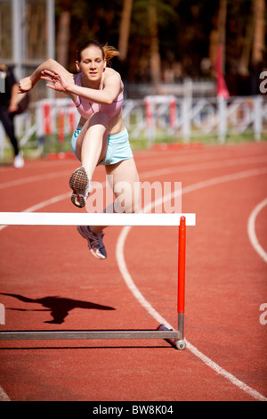 Bild junge Frau läuft und immer bereit, über Barriere springen Stockfoto