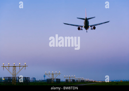 Amsterdam Schiphol Airport in der Abenddämmerung. Airplane Flugzeug nähert, Landung auf der Piste Kaagbaan. Stockfoto