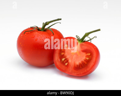 Anordnung eine ganze Tomate und eine Hälfte auf einem weißen Hintergrund mit Wassertropfen und Stielen. Stockfoto