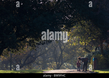 Lokalen Mutter und Kind mit Roller in Autumnal Brockwell Park, Herne Hill, South London. Stockfoto