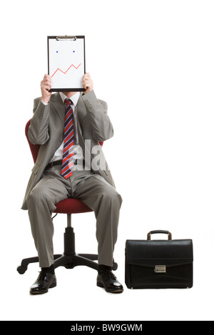 Porträt von gestressten Geschäftsmann sitzt auf Sessel versteckt sein Gesicht mit Papier zeigen, schlechte Laune oder Verwirrung Stockfoto