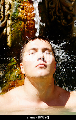 Porträt des jungen Mannes unter Strahl des Wassers die Freude Stockfoto