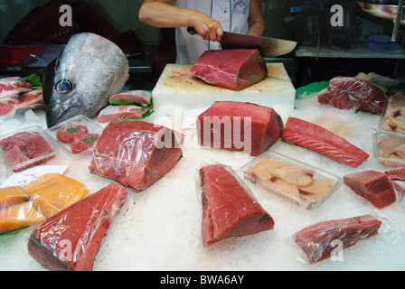 Frau schneidet ein Stück frischen Thunfisch mit großen Messer am Stall in La Boqueria-Markthalle in Barcelona, Spanien Stockfoto