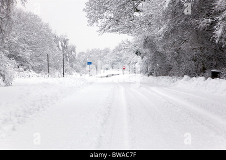 Eine schneebedeckte Straße mit No Entry und Exit Schilder in der Ferne, Schwerpunkt liegt auf den Schildern. Stockfoto