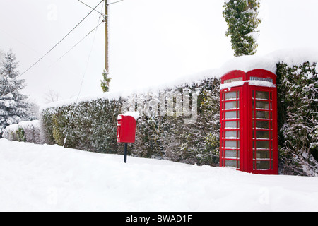Eine traditionelle rote englische Telefonzelle und Briefkasten nach einem schweren Schneefall. Stockfoto