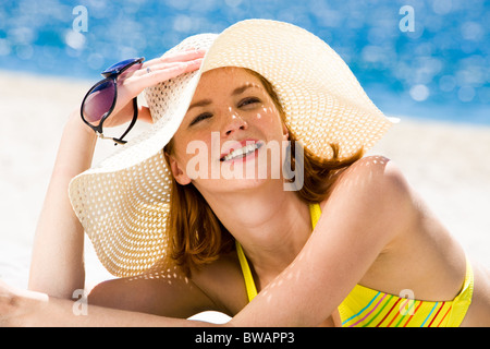 Foto von ruhenden Frau mit Hut, Sonnenbrille halten und Sonnenbaden Stockfoto