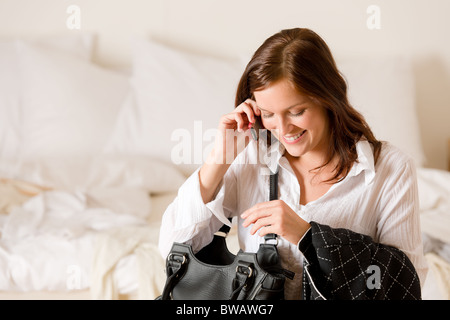 Am Telefon - Frau zu Hause im Schlafzimmer auf dem Bett sitzend Stockfoto