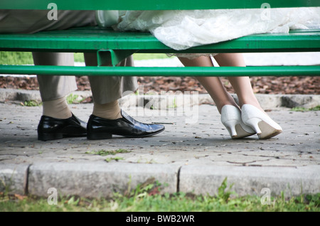 Nahaufnahme der Beine des neu vermählten unter der Sitzbank im Park während der Hochzeit Stockfoto