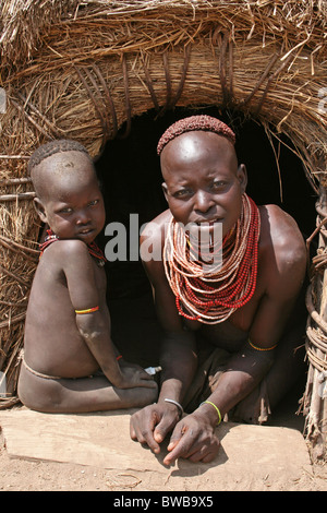 Karo-Stamm Frau mit Baby am Eingang zu ihrer Hütte, Omo-Tal, Äthiopien Stockfoto