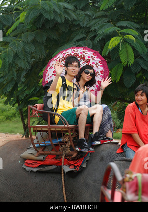 Elefantenritt. Junge chinesische Touristen-paar mit Regenschirm auf Elefanten in Pattaya, Thailand, Oktober 2010 Stockfoto