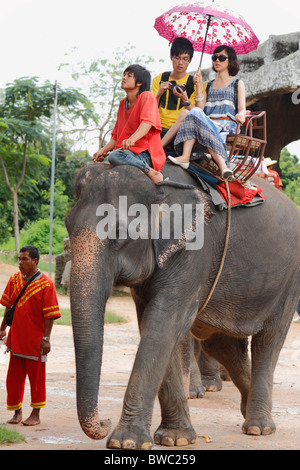 Elefantenritt. Junge chinesische Touristen-paar mit Regenschirm auf Elefanten in Pattaya, Thailand, Oktober 2010 Stockfoto