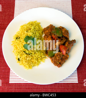 Essen, gekocht, Curry, indische Chicken Jalfrezi curry mit gelben Pilau Reis auf einem weißen Teller. Stockfoto