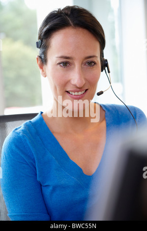 Empfangsdame hinter ihrem Schreibtisch Lächeln Stockfoto