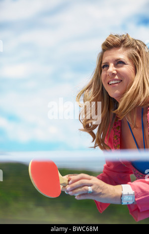 Lächelnde ältere Frau Tischtennis spielen Stockfoto